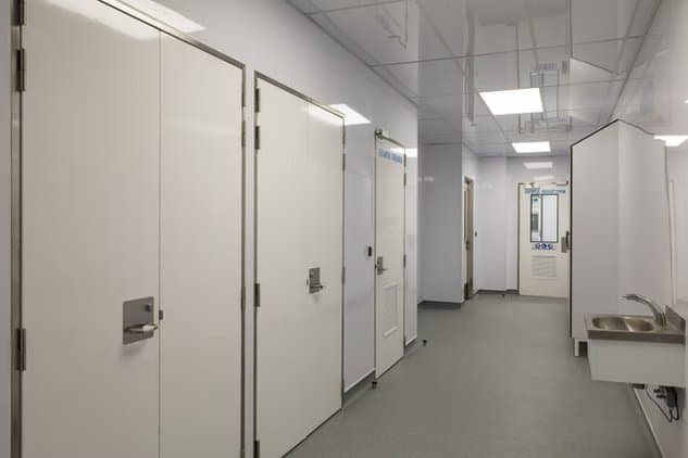 Commercial facility corridor lined with impervious panel walls and ceiling tiles cut to size from panels