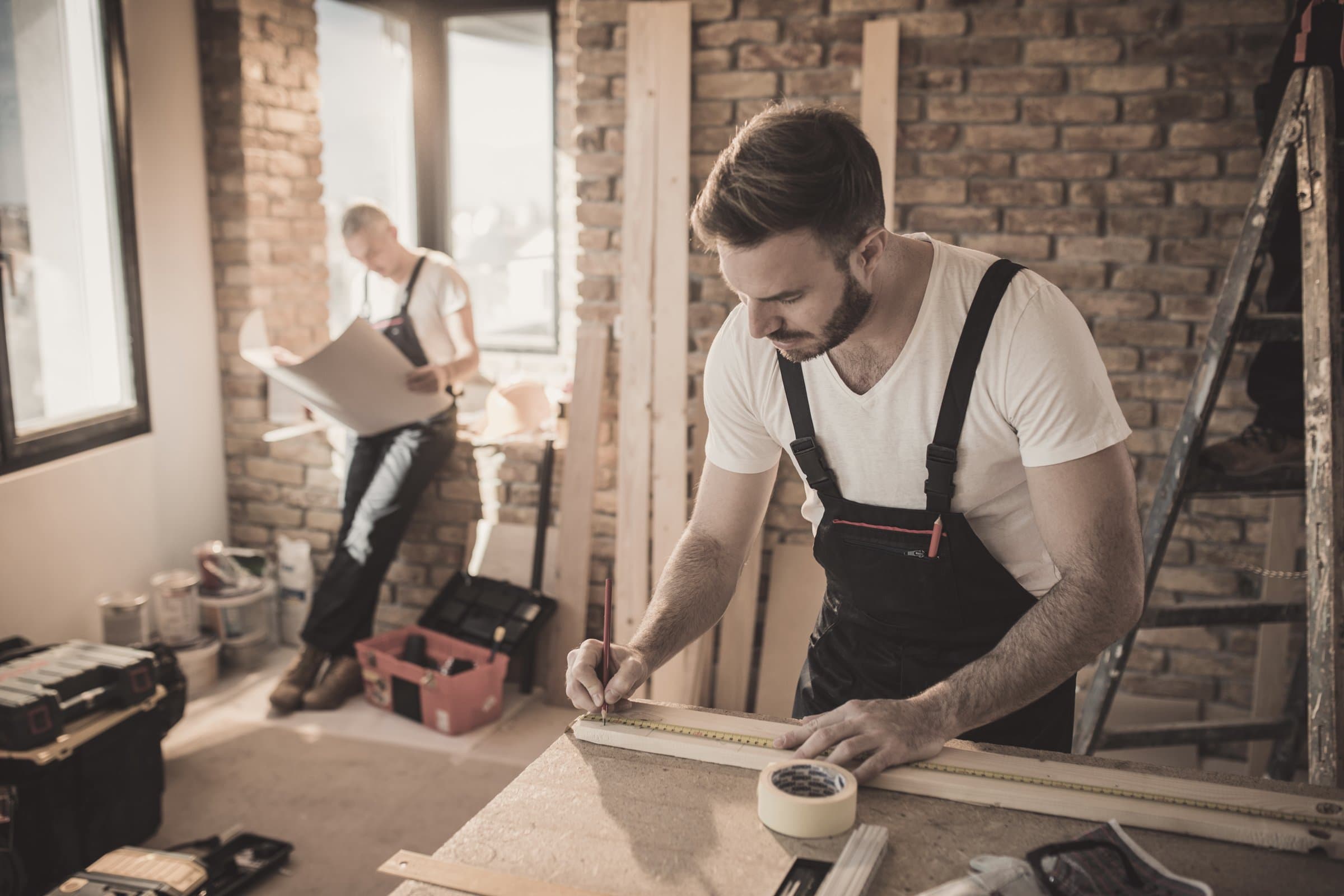 Installer measuring and marking panels on site during a renovation