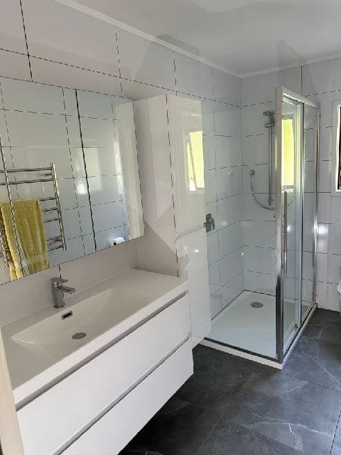 Shower and vanity lined with Hydratile tile-pattern panels — no grout lines to maintain